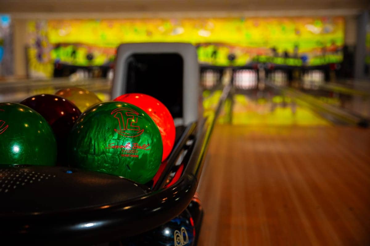 Bile de bowling pe retur, cu pistele în fundal